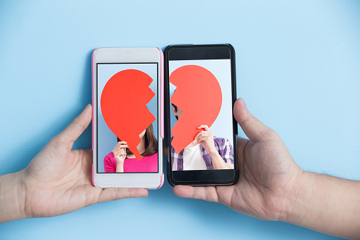 hand take smart phone with young couple take broken heart in screen on blue background