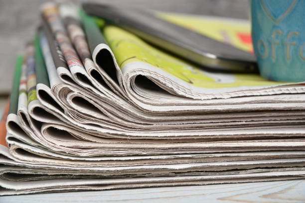 istock Stacked and piled up newspapers on a wooden table background with coffee cup 690859400