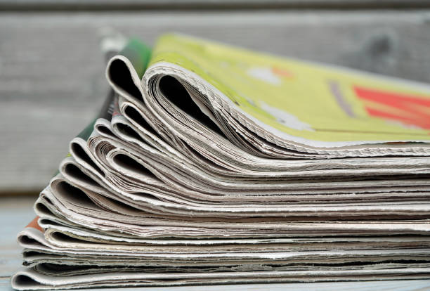 istock Stacked and piled up newspapers on a wooden table background 690859490