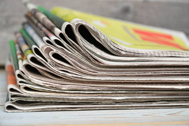 istock Stacked and piled up newspapers on a wooden table background 690859584