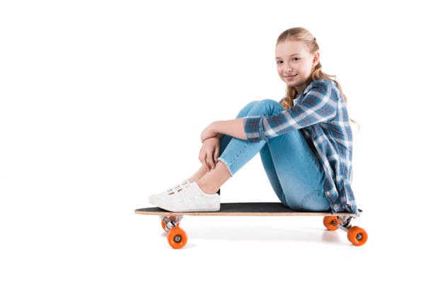 istock happy girl sitting on skateboard isolated on white in studio 690867670