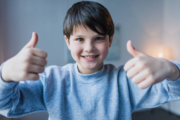 istock Cute little boy showing thumbs up and smiling at camera 690867890