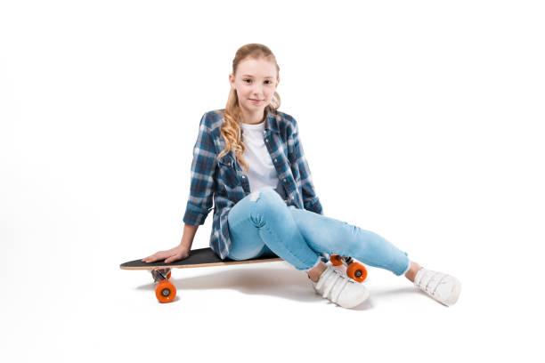 istock happy girl sitting on skateboard isolated on white in studio 690870996