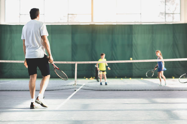 istock Male coach playing tennis with kids 690879508