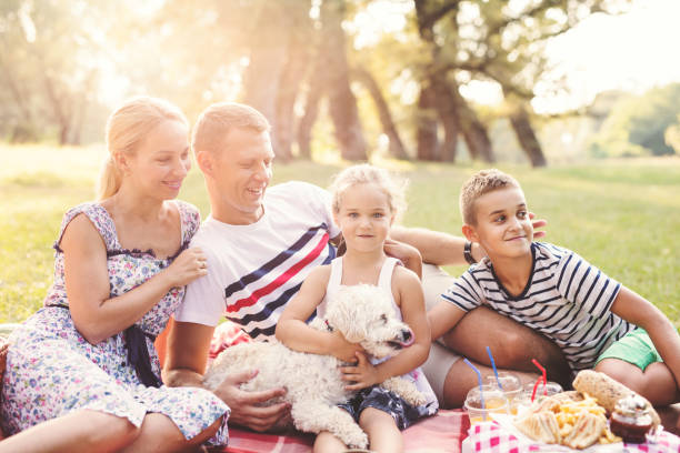 istock Young happy family enjoying picnic outdoors withe their cute dog 690879968