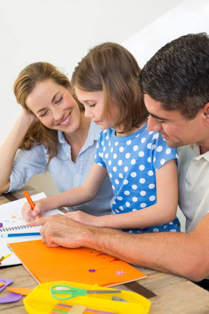 istock Parents looking at daughter coloring 690880218