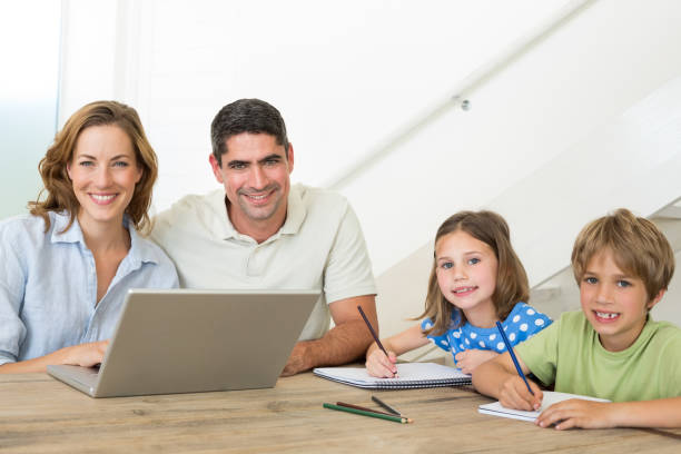 istock Parents with laptop while children coloring at table 690883790