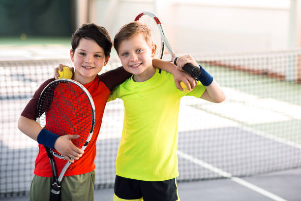 enfants heureux divertissants sur un court de tennis - tennis child teenager childhood photos et images de collection