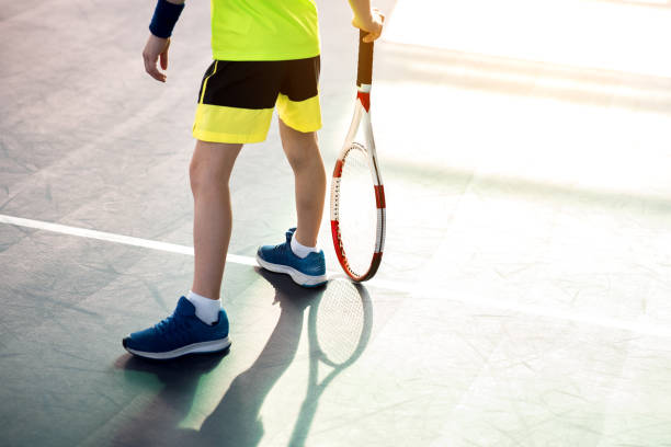 garçon jouant au tennis sur le terrain de jeu - tennis child teenager childhood photos et images de collection