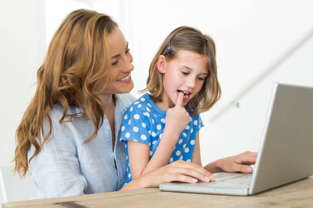 istock Mother teaching daughter to use laptop 690886254