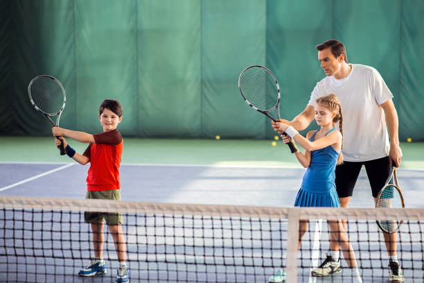 istock Trainer explaining children how to play tennis 690886314