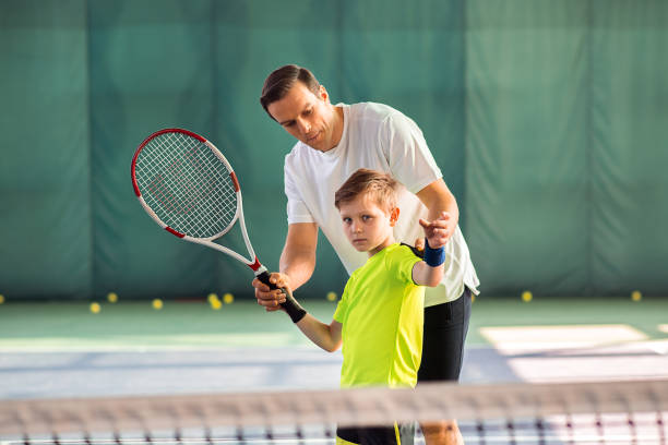 niños de enseñanza hábil entrenador sosteniendo la raqueta - tennis child childhood sport fotografías e imágenes de stock