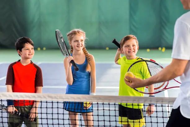 Photo of Joyful pupils learning to play tennis