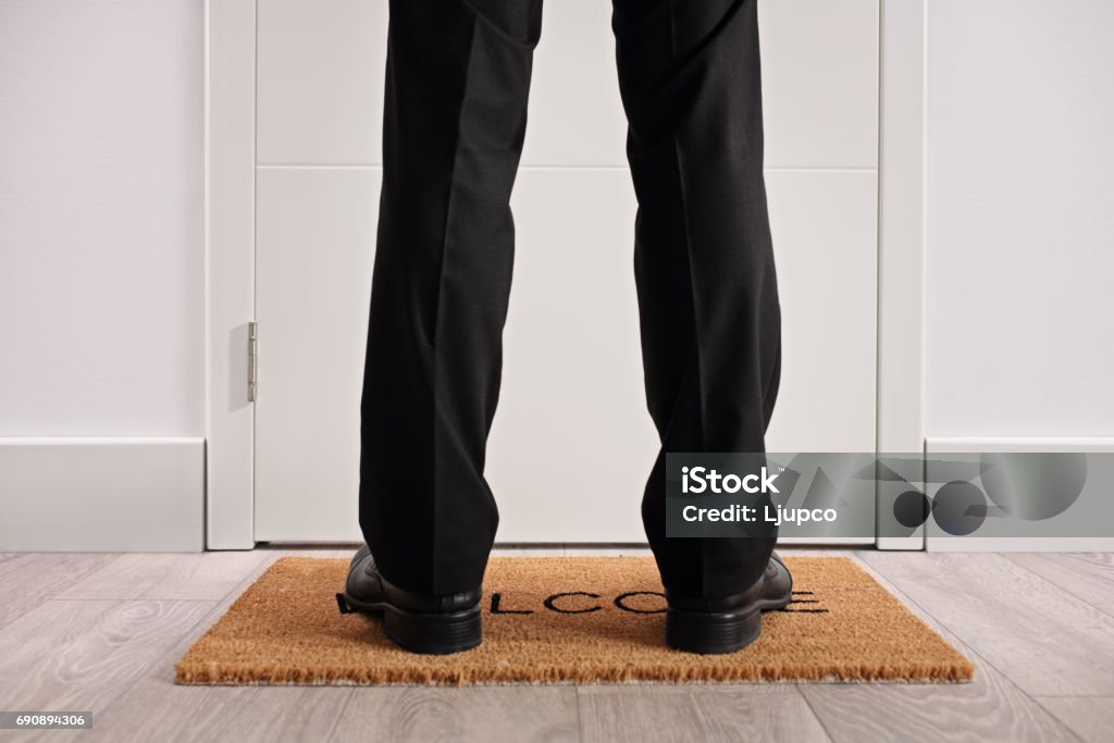 Persoon staande op een deurmat voor gesloten deur - Royalty-free Voet Stockfoto Persoon staande op een deurmat voor gesloten deur - Royalty-free Voet Stockfoto