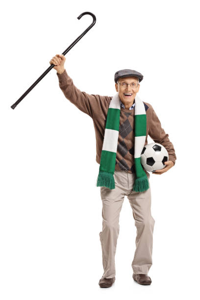 istock Overjoyed mature soccer fan holding a cane and cheering 690896468