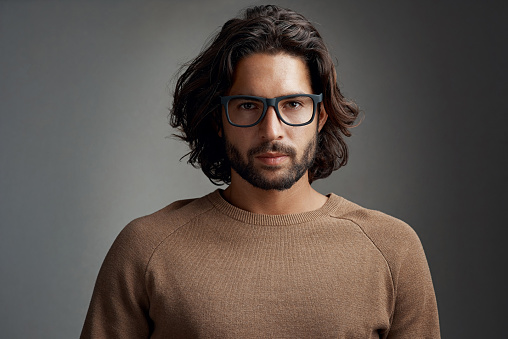 Studio shot of a handsome young man wearing glasses against a gray background