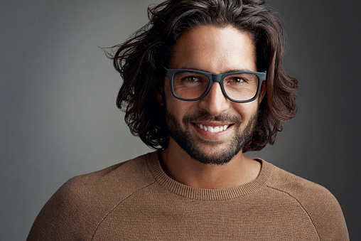 Studio shot of a handsome young man wearing glasses against a gray background