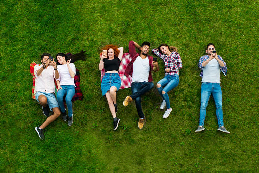 Group of young people laying on the grass, happy, smiling