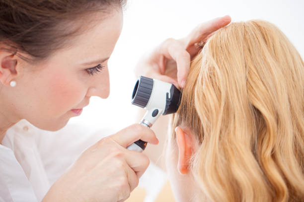 istock Doctor inspecting patient Scalp with a Dermatoscope 690903820