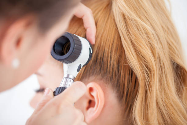 istock Doctor inspecting Patient Scalp with a Dermatoscope 690903836