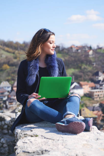 istock Smart student using her laptop in the street 690907166