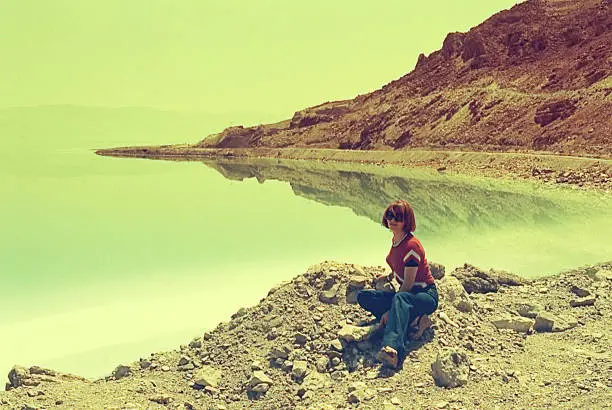 Vintage image of a woman sitting beside the Dead Sea in Israel during a trip in the seventies