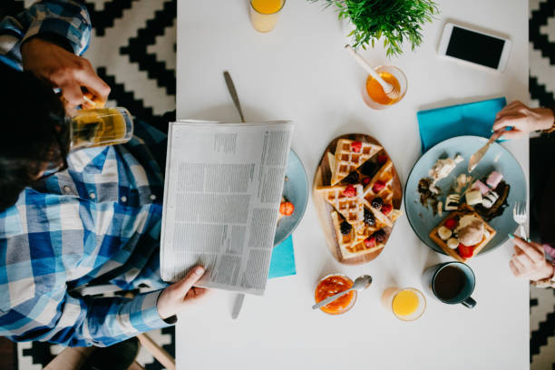 The man is reading the newspaper during breakfast