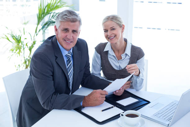 istock Smiling businessman with secretary checking file 691094798