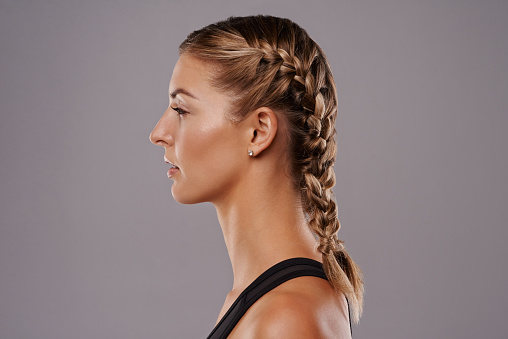 Studio shot of a young woman with her hair braided against a gray background
