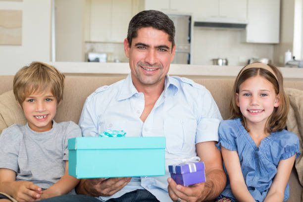 istock Father holding gifts by children on sofa 691099964