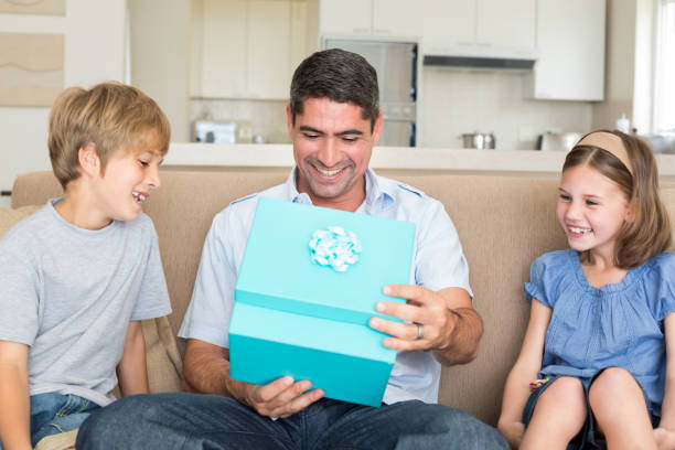istock Father opening gift given by children on sofa 691099990
