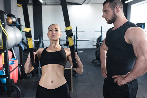 istock sportswoman training with trx resistance band with serious trainer 691114420