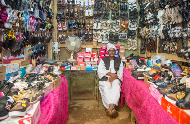 sudanese shoe salesman Khartoum, Sudan, December 18th, 2015: sudanese man in traditional clothing, at his shoe shop khartoum stock pictures, royalty-free photos & images