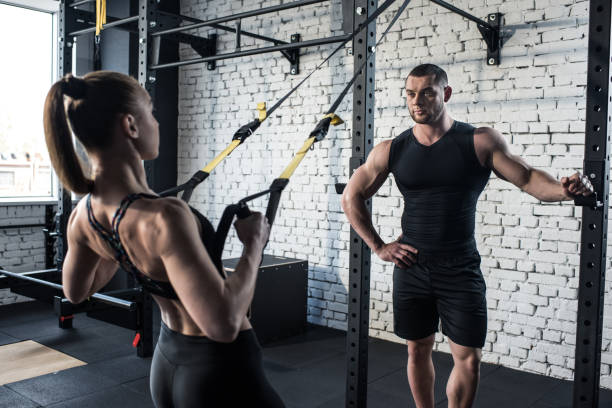 istock sportswoman training with trx resistance band with serious trainer 691115398
