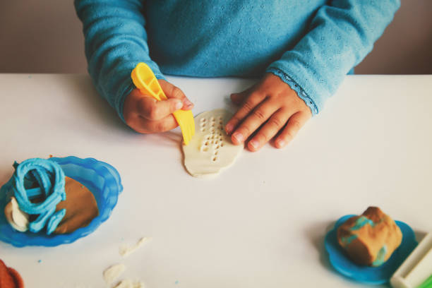 Child playing with clay molding shapes, learning concept
