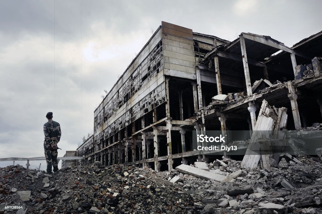 Soldat en uniforme militaire se dresse sur les ruines - Photo de Guerre libre de droits