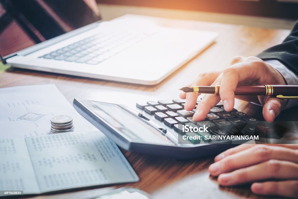 Businessman's hands with calculator and cost at the office and Financial data analyzing counting on wood desk Debt Stock Photo