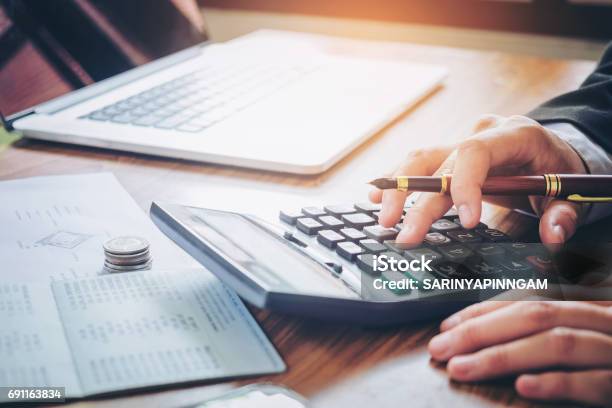 Businessmans Hands With Calculator And Cost At The Office And Financial Data Analyzing Counting On Wood Desk Stock Photo - Download Image Now