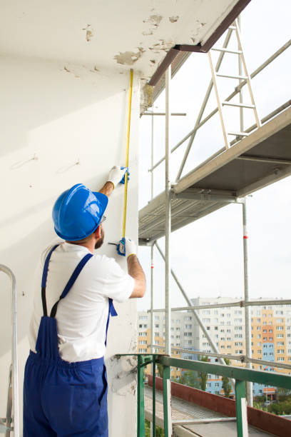 istock Construction worker in a protective helmet and work attire measures scaffolding on a construction site. 691177384