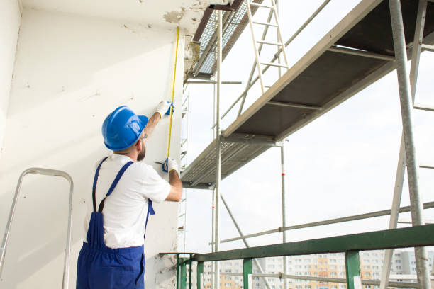 istock Construction worker in a protective helmet and work attire measures scaffolding on a construction site. 691177390