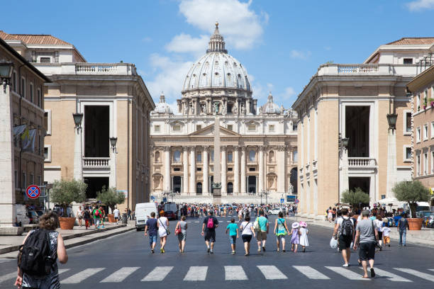 VATICAN CITY, ITALY - July 26, 2015:  Tourists approach St. Peter's Square in Vatican City.  Vatican City is a walled enclave within the city of Rome and home to the Pope.