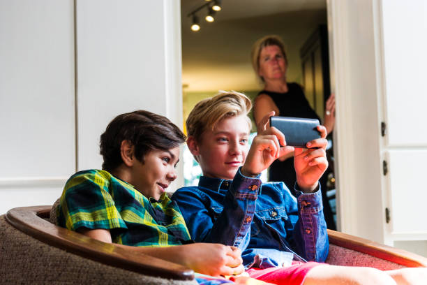 istock Mother with slightly concerned look on her face watching boys using the internet on a phone 691189732