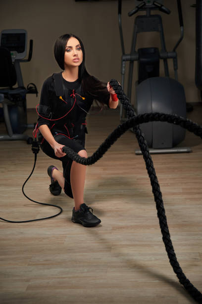 istock Brunette girl in EMS suit doing wave using rope. Glow effect 691194260