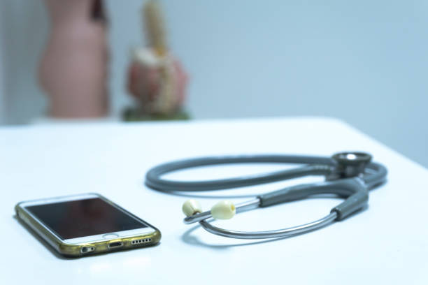 a stethoscope and cellphone on the doctor exam table - telephone doctor medical exam healthcare and medicine imagens e fotografias de stock