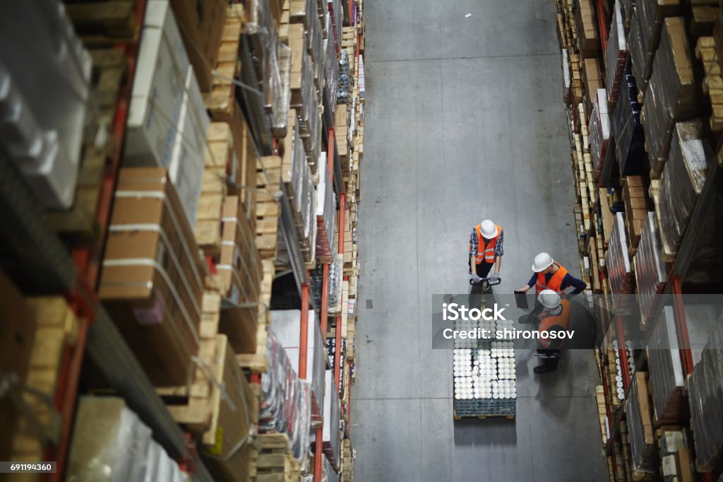 Loaders at work Group of workers in uniform and helmets having talk in aisle Freight Transportation Stock Photo