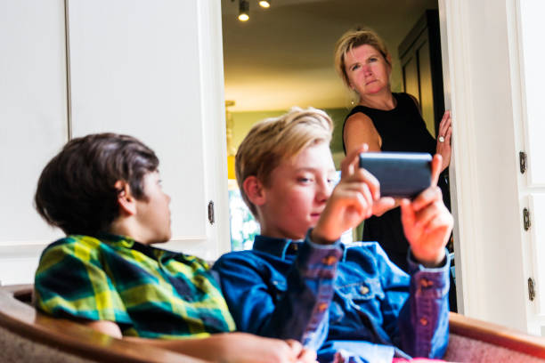 istock Mother with slightly concerned look on her face watching boys using the internet on a phone 691194674