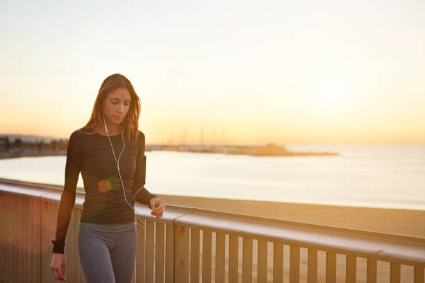 istock Woman walking by railings at beach during sunset 691203064