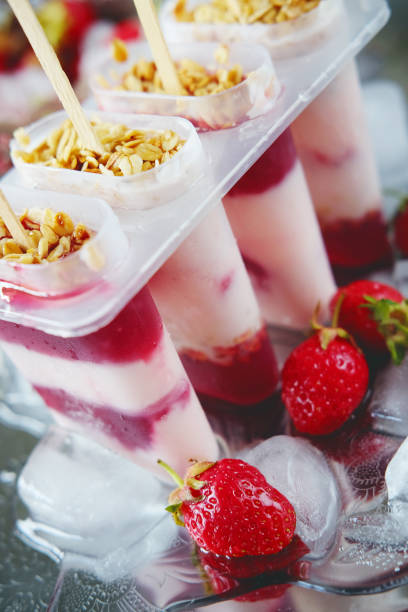 istock Frozen yoghurt popsicles with strawberries and ice on silver plate 691210628