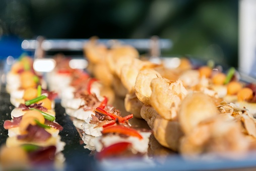Horizontal color close-up image of party food arranged on a silver tray. Variation of canapes ready to eat.