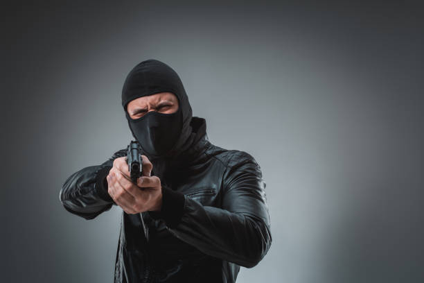 ladrón con una pistola, disparo de estudio - gun currency crime mafia fotografías e imágenes de stock